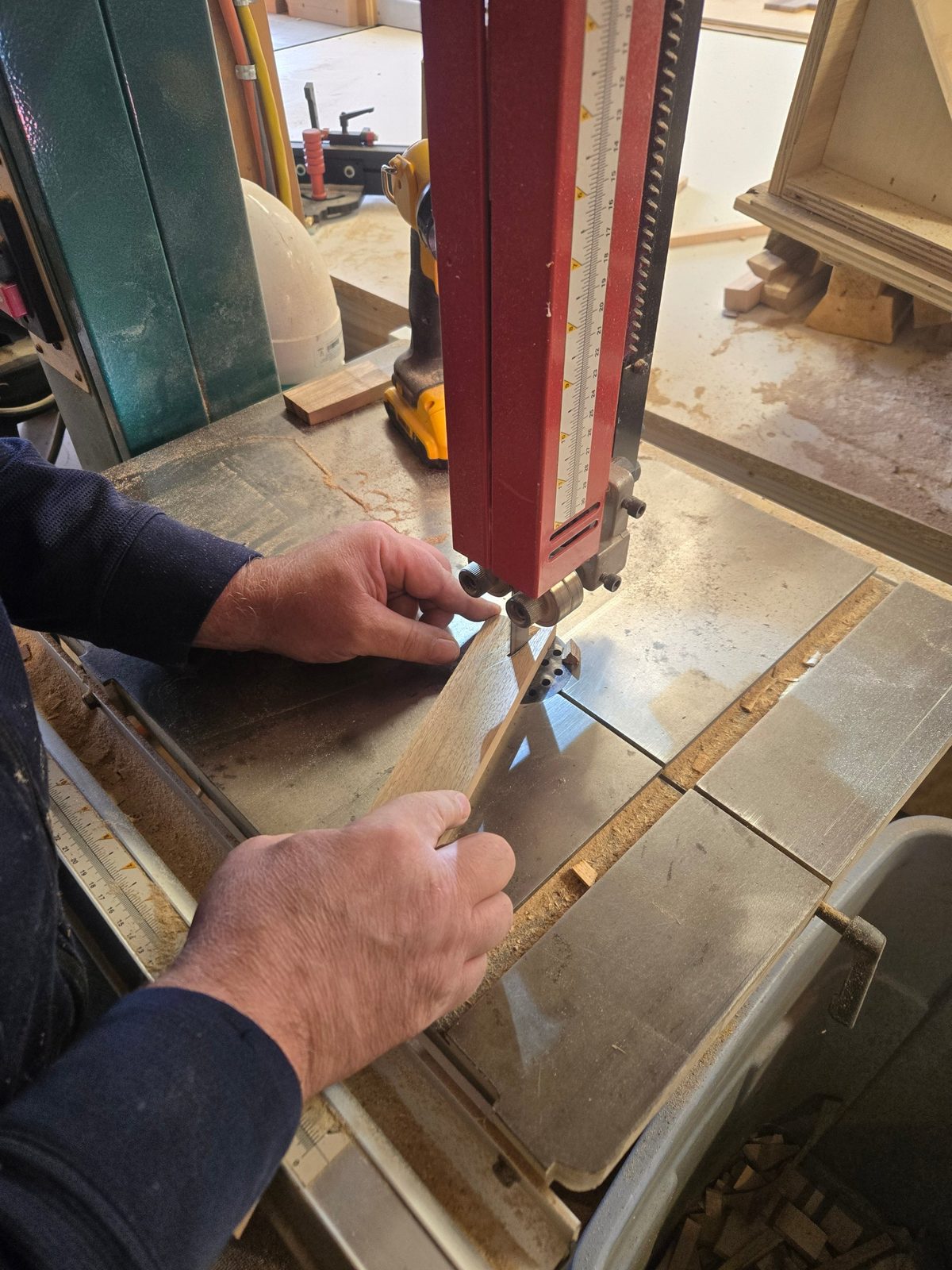 Hands guiding wood through the bandsaw